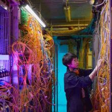 Wide angle side view at young network technician connecting wires and cables in server room, copy space
