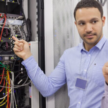 Two technicians looking at wiring of servers in data center