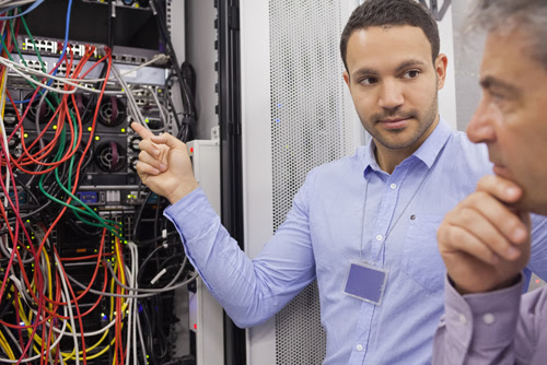 Two technicians looking at wiring of servers in data center